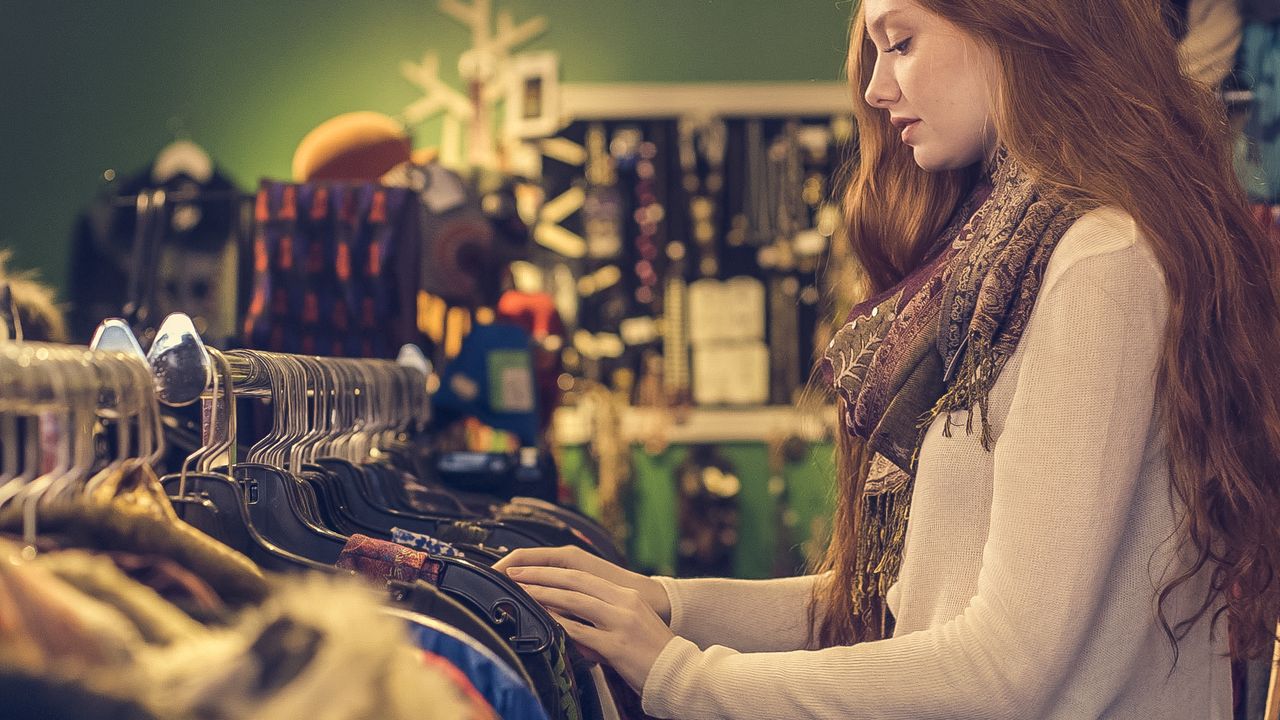 A young woman shops for fashion clothing in a vintage-themed store.